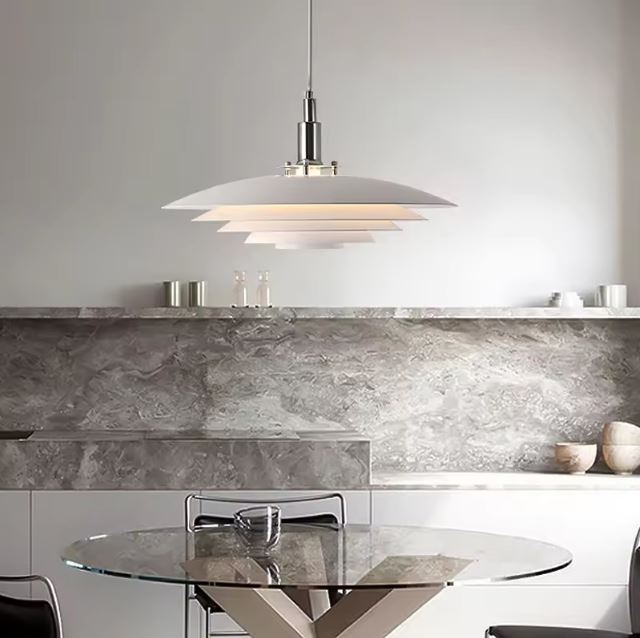 Suspension Morandi blanche suspendue au-dessus d’une table ronde en verre dans une cuisine au style minimaliste.