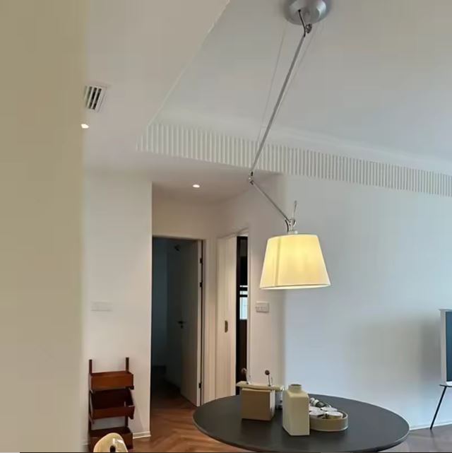 Suspension orientable avec bras articulé, idéale pour un éclairage ciblé au-dessus d’une table ronde dans un intérieur contemporain épuré.