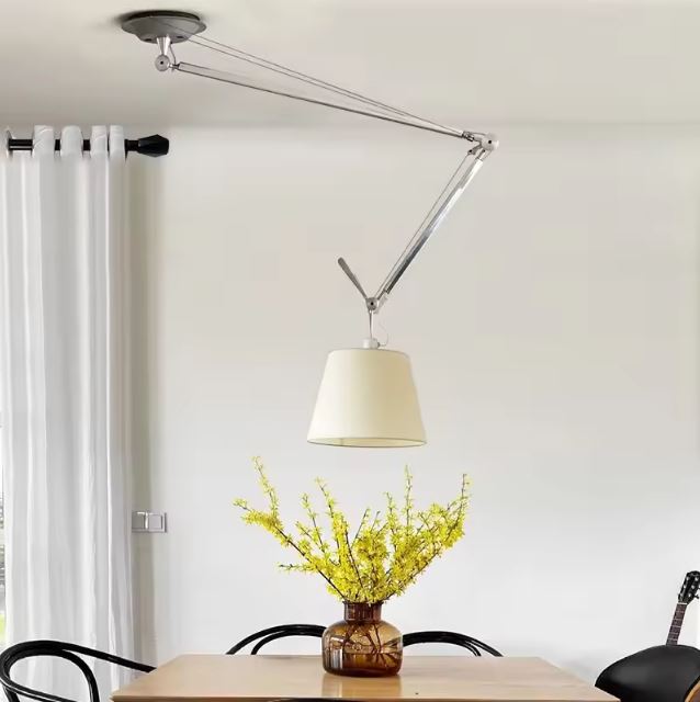 Suspension orientable avec bras articulé au-dessus d’une table en bois, idéale pour une salle à manger au style naturel et lumineux.