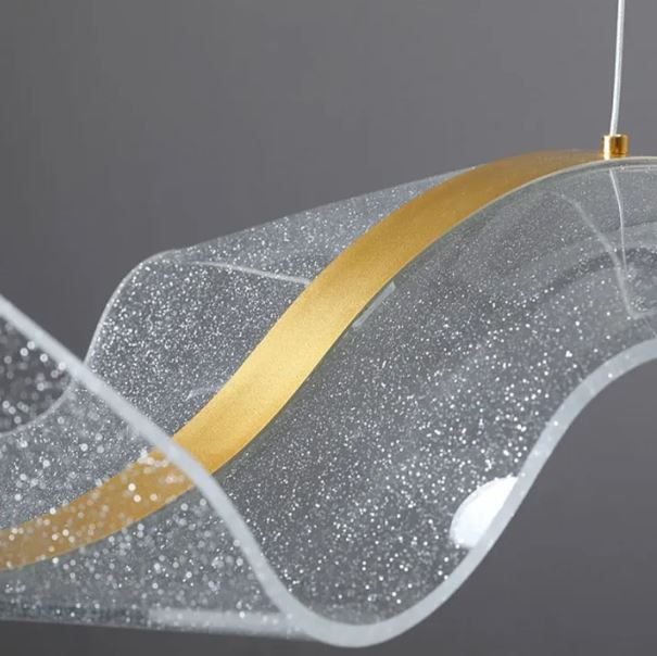 Détail d’une suspension voile avec finition brillante et ligne dorée, mettant en valeur son mouvement fluide et sa finesse sculpturale.