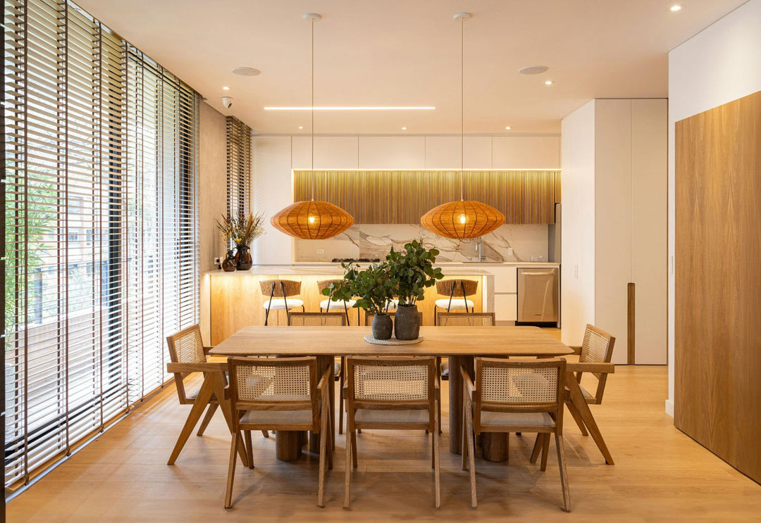 Salle à manger chaleureuse avec table en bois et suspensions en rotin, créant une atmosphère lumineuse et naturelle.