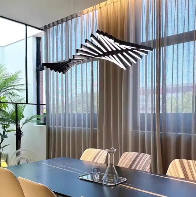 Suspension architecturale en barres noires ondulées au-dessus d’une grande table, dans un bureau contemporain lumineux et structuré.