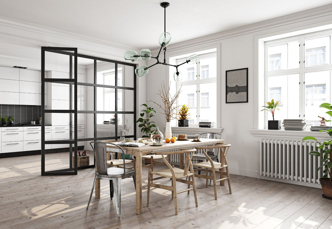 Suspension moderne à bras articulés avec globes en verre au-dessus d’une salle à manger lumineuse.