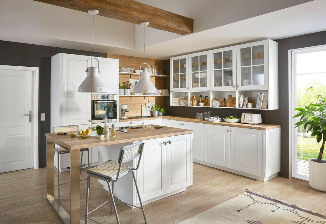 Cuisine ouverte lumineuse avec deux suspensions au-dessus de l’îlot, bois clair et façades blanches pour une ambiance chaleureuse et cohérente.