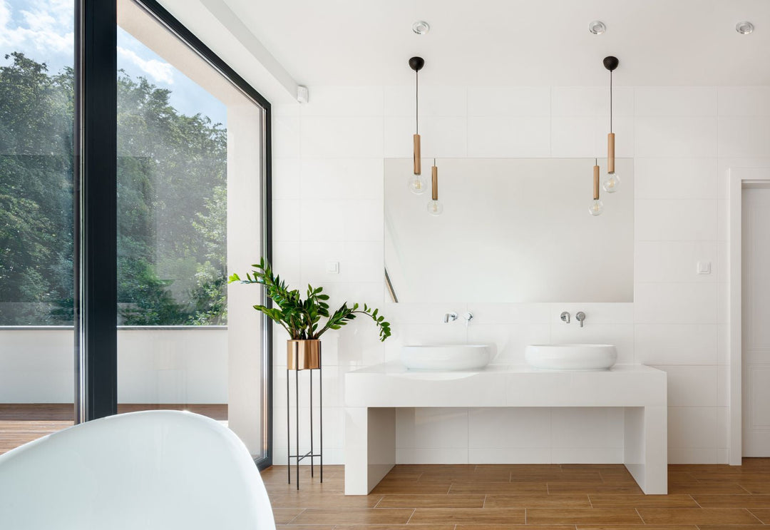Deux suspensions légères au-dessus d’une double vasque dans une salle de bain claire, pour une lumière nette, douce et visuellement apaisante.