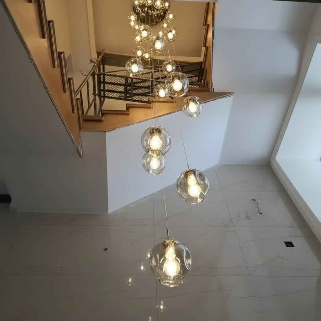 Luminaire haut de gamme avec globes en verre suspendus à différentes longueurs créant un effet décoratif spectaculaire dans une cage d'escalier