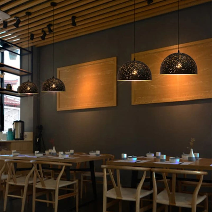 Agencement de restaurant professionnel avec des suspensions constellation perforées en métal alignées.