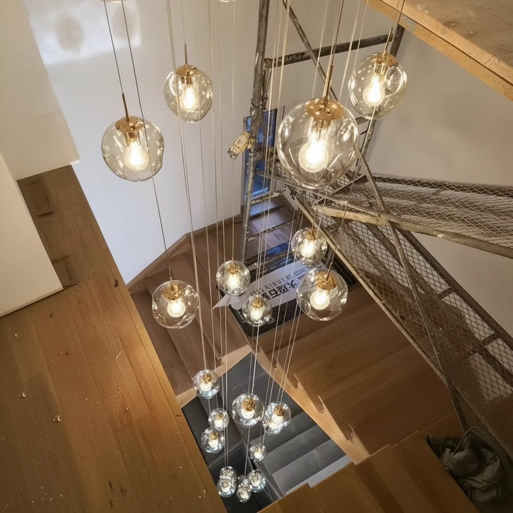 Lustre contemporain composé de multiples sphères en verre lumineuses suspendues au-dessus d'un escalier intérieur élégant