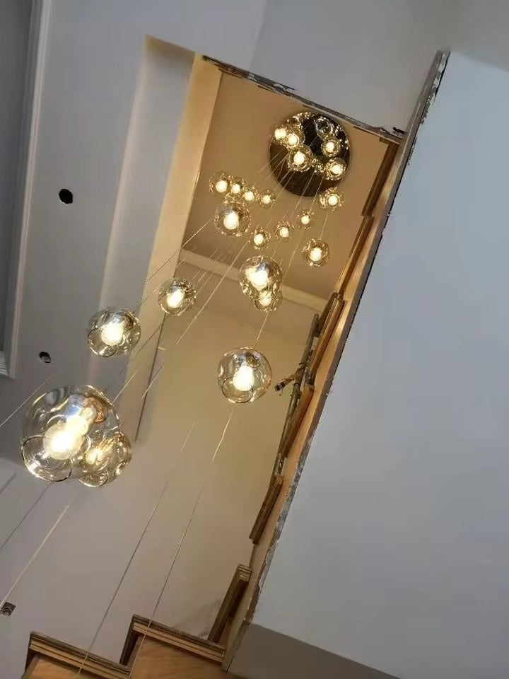 Lustre en cascade avec plusieurs globes en verre transparent installés dans une cage d'escalier moderne