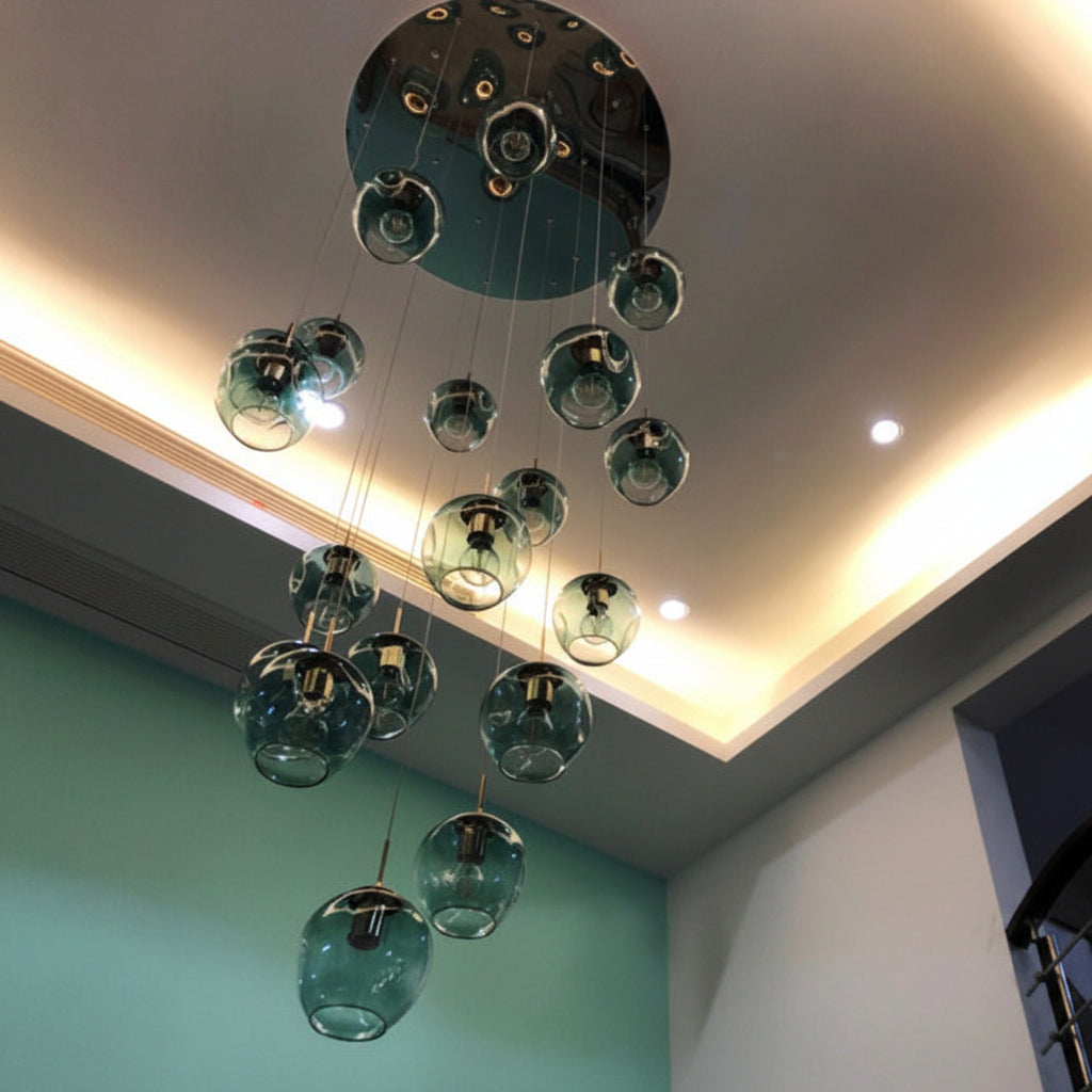 Suspension élégante composée de globes en verre transparent avec dégradé bleu suspendus à différentes hauteurs dans une entrée moderne