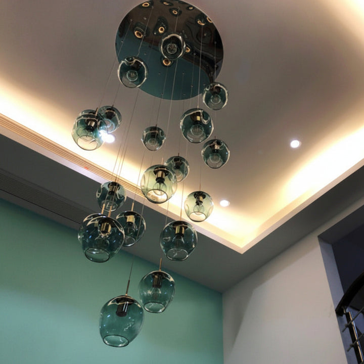 Suspension élégante composée de globes en verre transparent avec dégradé bleu suspendus à différentes hauteurs dans une entrée moderne