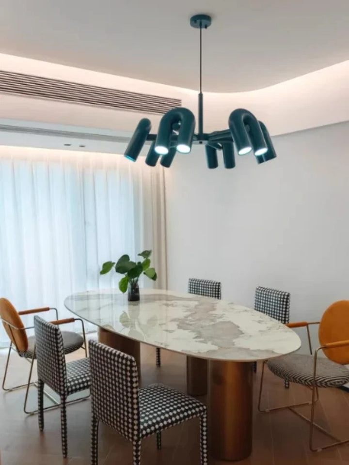 Suspension design tubulaire aux courbes en U en finition bleu installée au-dessus d'une table à manger, apportant un éclairage moderne et une touche d'élégance à la salle à manger.