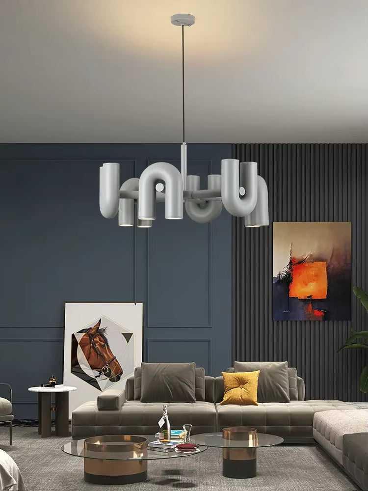 Suspension design tubulaire aux courbes en U en finition gris mat installée au-dessus d'un salon moderne, diffusant un éclairage élégant et créant une ambiance chaleureuse.
