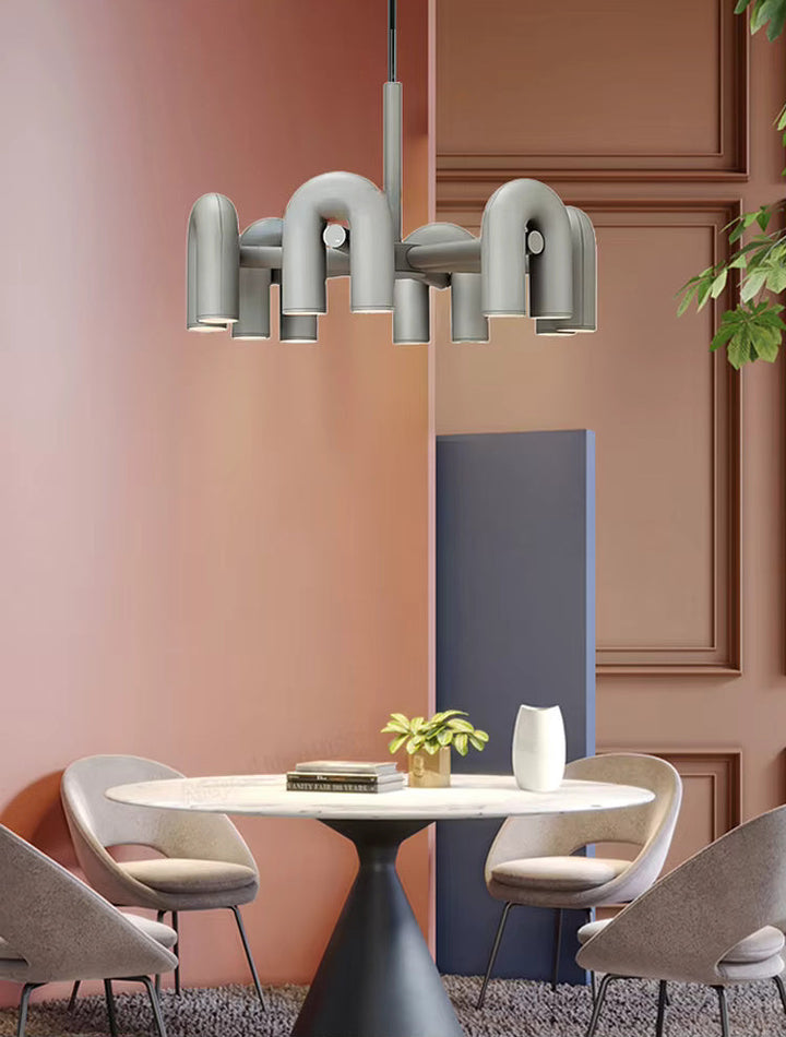 Suspension design tubulaire aux courbes en U en finition gris mat installée au-dessus d'une table moderne, offrant un éclairage élégant et un style contemporain.