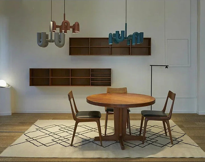 Suspension design tubulaire aux courbes en U en finition gris mat suspendue au-dessus d'une table moderne, offrant un éclairage élégant et un style contemporain.