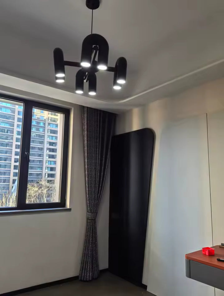 Suspension design tubulaire aux courbes en U en finition noir mat installée dans une chambre moderne, apportant un éclairage élégant et une ambiance contemporaine.