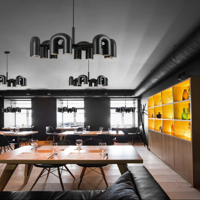 Suspension design tubulaire aux courbes en U en finition noir mat installée dans un restaurant moderne, apportant un éclairage élégant et une ambiance contemporaine.