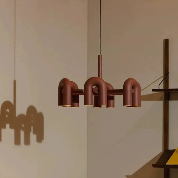 Suspension design tubulaire aux courbes en U en finition orange suspendue au plafond, mettant en valeur son design moderne et ses lignes élégantes.