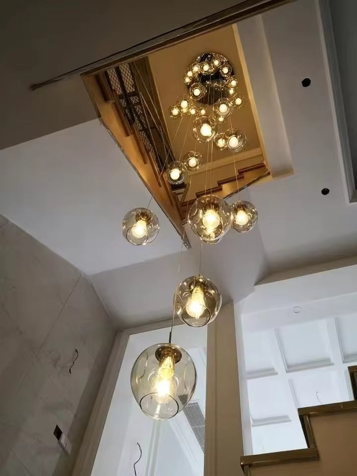 Suspension élégante composée de globes en verre suspendus au-dessus d'un escalier contemporain à plafond haut