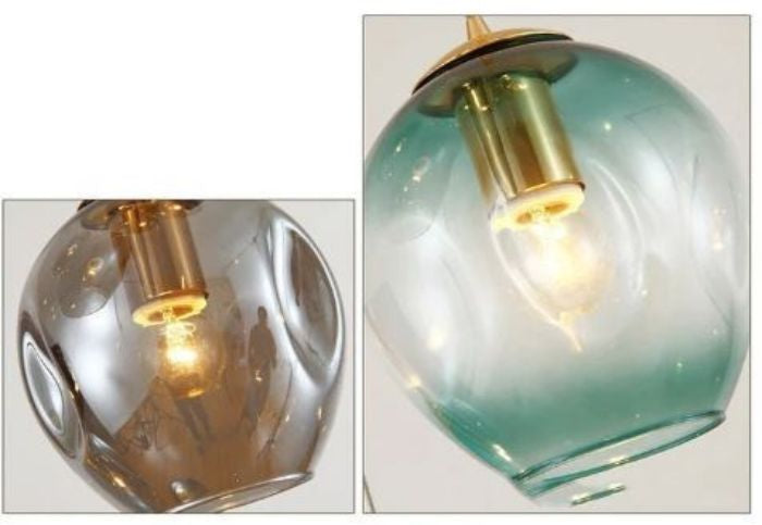 Gros plan sur une suspension moderne avec globe en verre fumé et support en chassis doré, diffusant une lumière chaleureuse