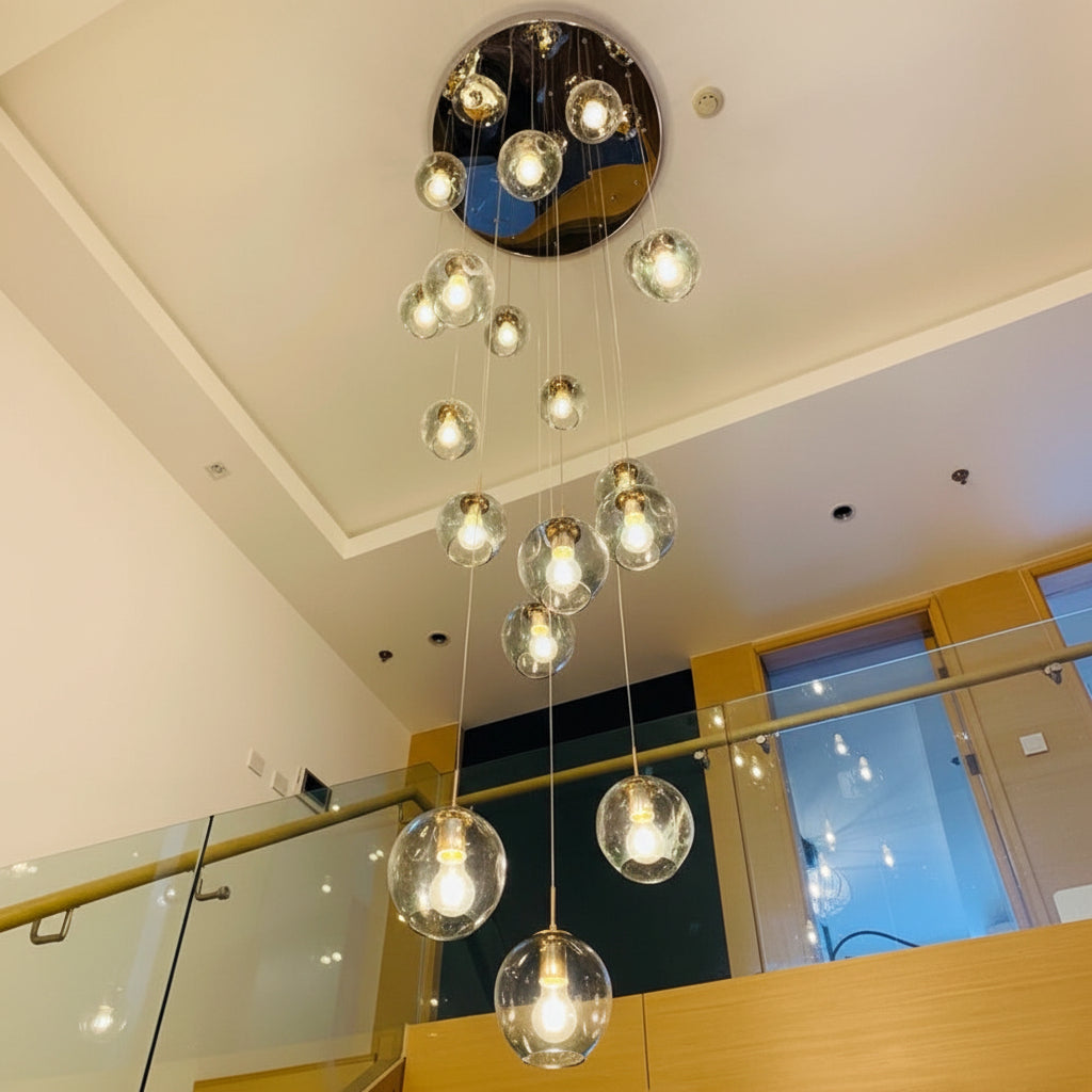 Ensemble de suspensions en verre transparent disposées en cascade dans un espace ouvert avec escalier et plafond double hauteur