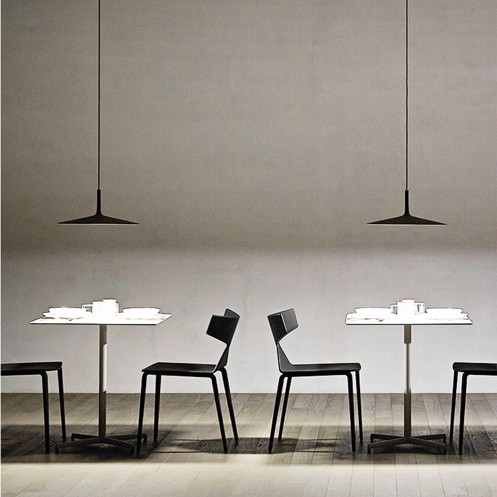 Alignement de luminaires UFO noirs au-dessus d'un comptoir de restaurant design.