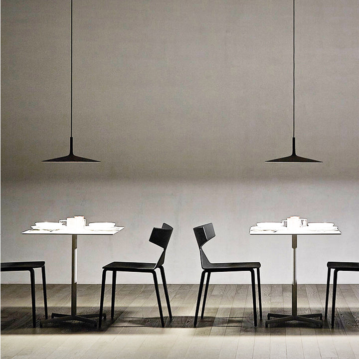 Alignement de luminaires UFO noirs au-dessus d'un comptoir de restaurant design.