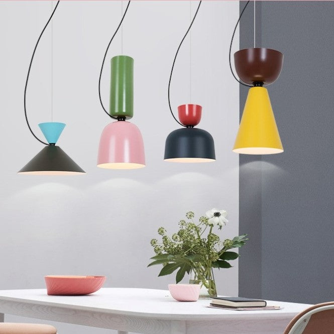 Alignement de suspensions en métal coloré au-dessus d'une table à manger, créant un espace convivial et design.