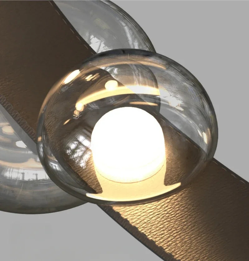 Détail rapproché d'une sphère lumineuse en verre soufflé transparent intégrée à un ruban de cuir tressé haut de gamme.