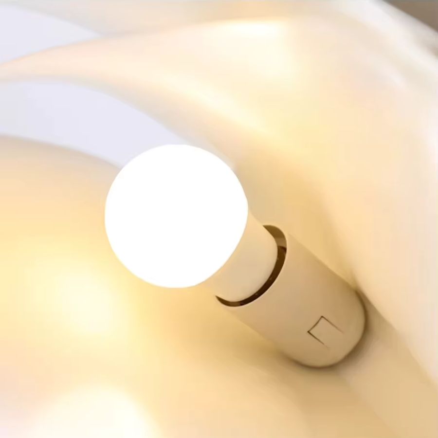 Détail de l’ampoule d’une suspension design en forme de livre ouvert diffusant une lumière chaude et douce