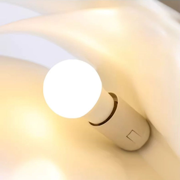Détail de l’ampoule d’une suspension design en forme de livre ouvert diffusant une lumière chaude et douce