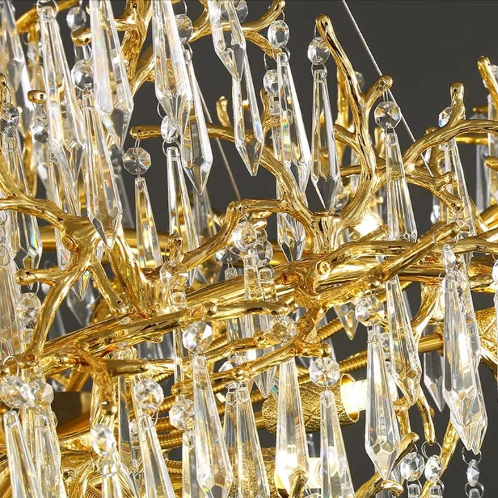 Détail des branches dorées sculptées et des longues pampilles de cristal qui donnent au lustre son allure précieuse et organique