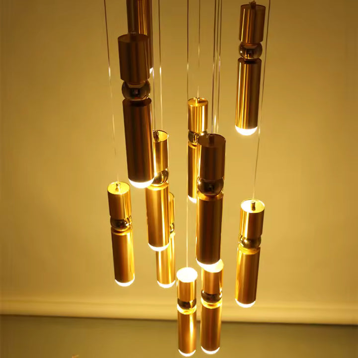 Cascade de luminaires dorés allongés à sphère centrale, diffusant une lumière chaude au style sculptural