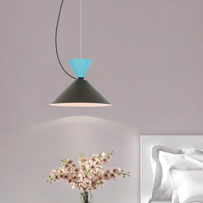 Coin nuit cosy illuminé par une suspension géométrique élégante en métal coloré surplombant un délicat bouquet de fleurs séchées.