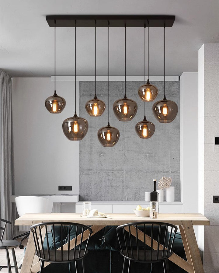 Composition de luminaires en verre fumé structurant l'espace d'une cuisine ouverte.