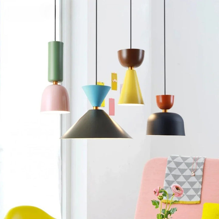 Composition colorée de luminaires suspendus en métal associant des teintes pastel et vives dans un intérieur lumineux et créatif.