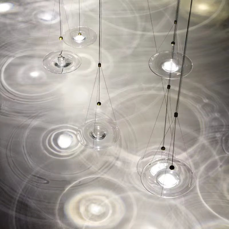 Composition aérienne de suspensions disque en verre transparent créant des reflets lumineux au style design