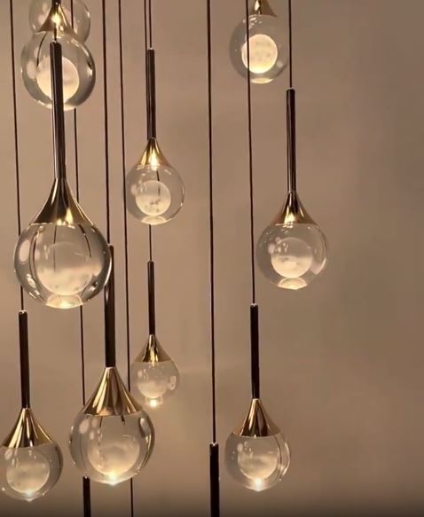 Composition de suspensions dorées, globes en verre transparent à cœur opalin, ambiance chic contemporaine.