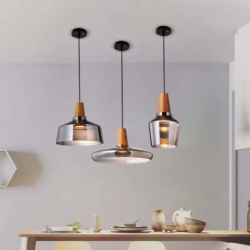 Au-dessus de la table, trois luminaires en verre fumé et bois composent un ensemble sculptural au style moderne