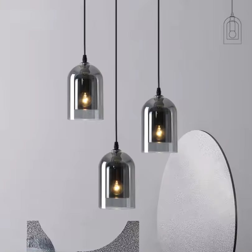 Trio de suspensions en verre fumé à hauteurs variées, aux reflets argentés et à l'allure sculpturale contemporaine.