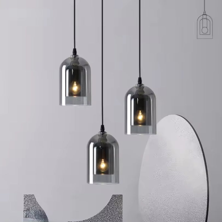 Trio de suspensions en verre fumé à hauteurs variées, aux reflets argentés et à l'allure sculpturale contemporaine.