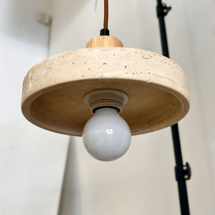 Vue en contre-plongée d'une suspension en pierre et bois avec son ampoule globe apparente au style japandi.