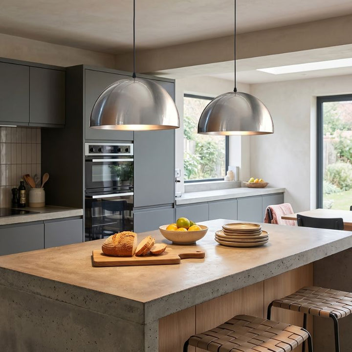 Suspensions design en métal argenté installées au-dessus d'un îlot de cuisine moderne.