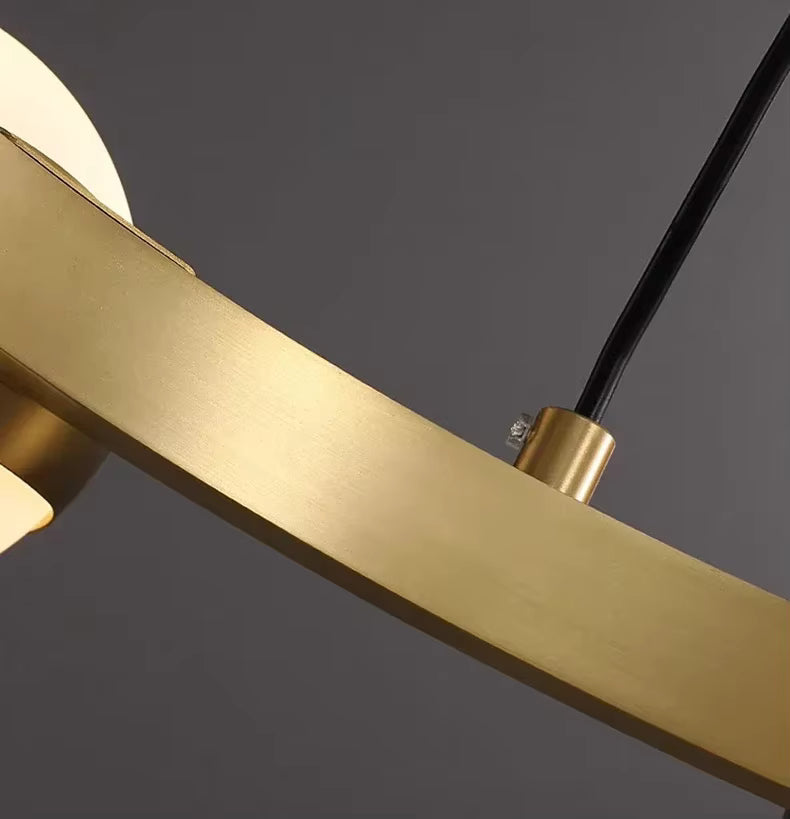 Finition en métal doré brossé sur l’anneau du lustre orbital, au design contemporain sobre et raffiné