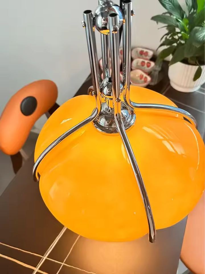Vue de dessus sur l’armature chromée enveloppant le dôme orange d'une suspension, avec un design Space Age sculptural et rétro