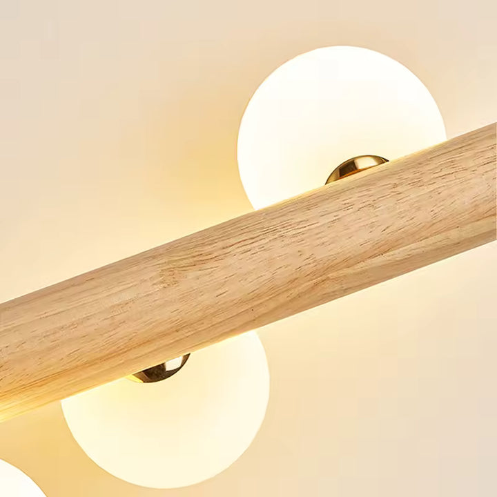 Gros plan sur le bois clair et les globes lumineux de la suspension, au style japandi naturel, doux et épuré.