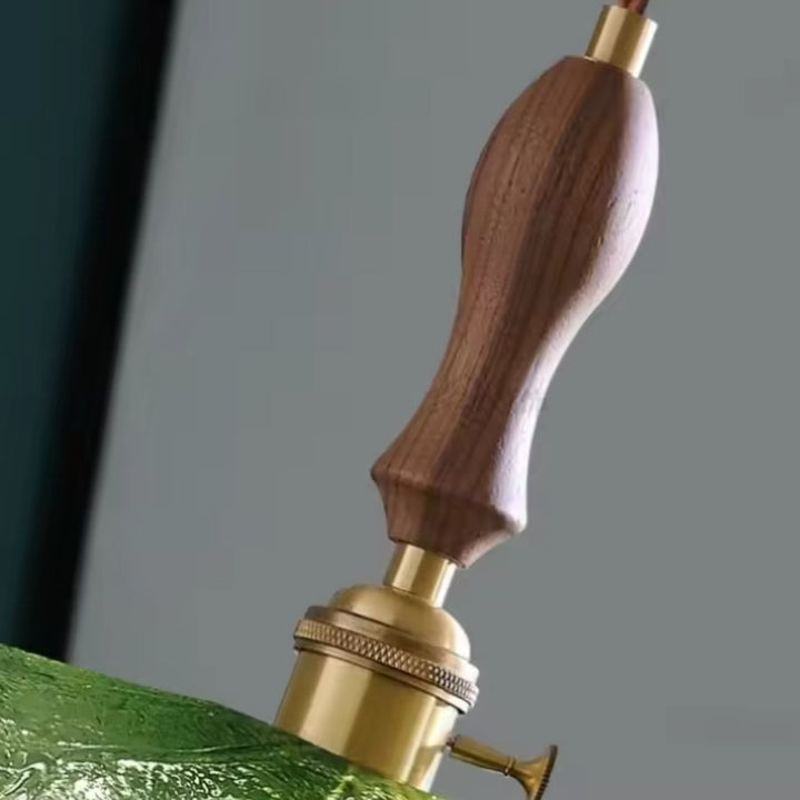 Détail de la poignée en bois de noyer et de la douille en laiton d’un luminaire botanique en verre vert