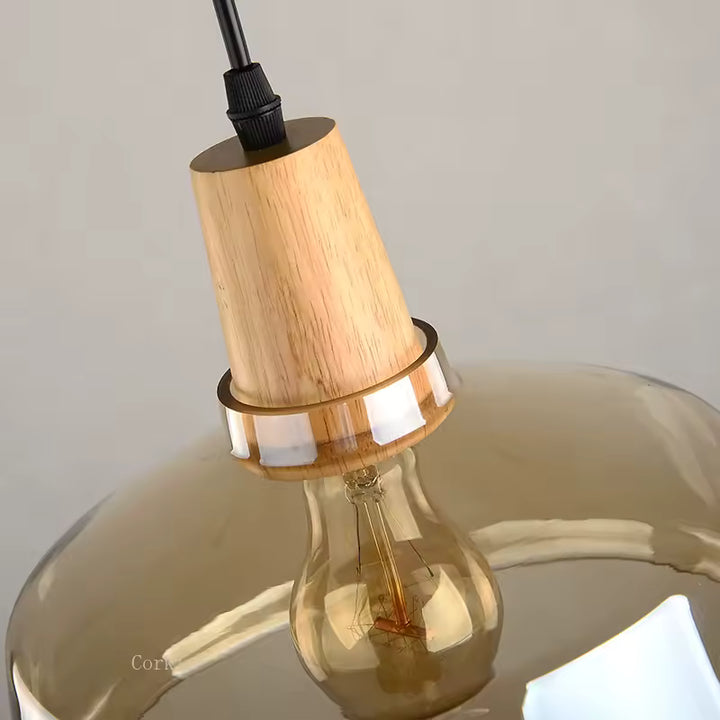 Gros plan sur le raccord en bois et le verre ambré d’un luminaire sculptural au design chaleureux et raffiné
