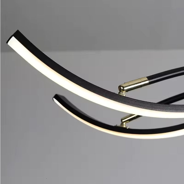 Gros plan sur les bras LED courbés d’un lustre araignée noir, au design contemporain avec finitions dorées.