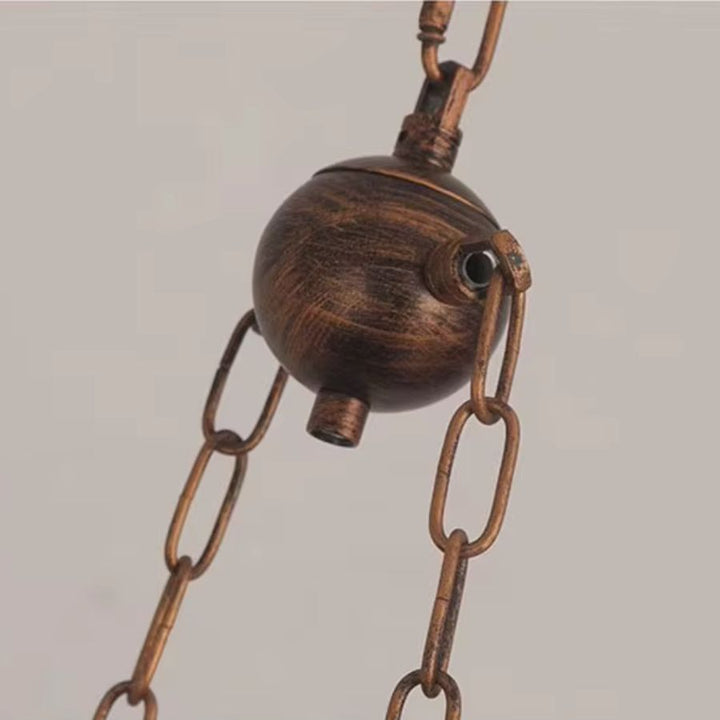 Gros plan sur le système de chaîne métallique réglable, au fini vieilli typique d’une suspension style atelier